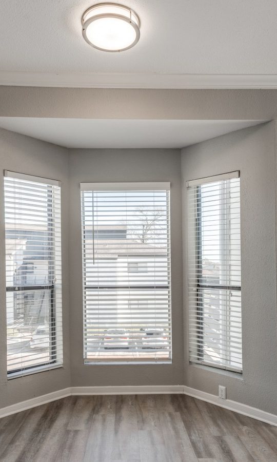 empty living room with hardwood floors and large windows at The Pearce on  Lake