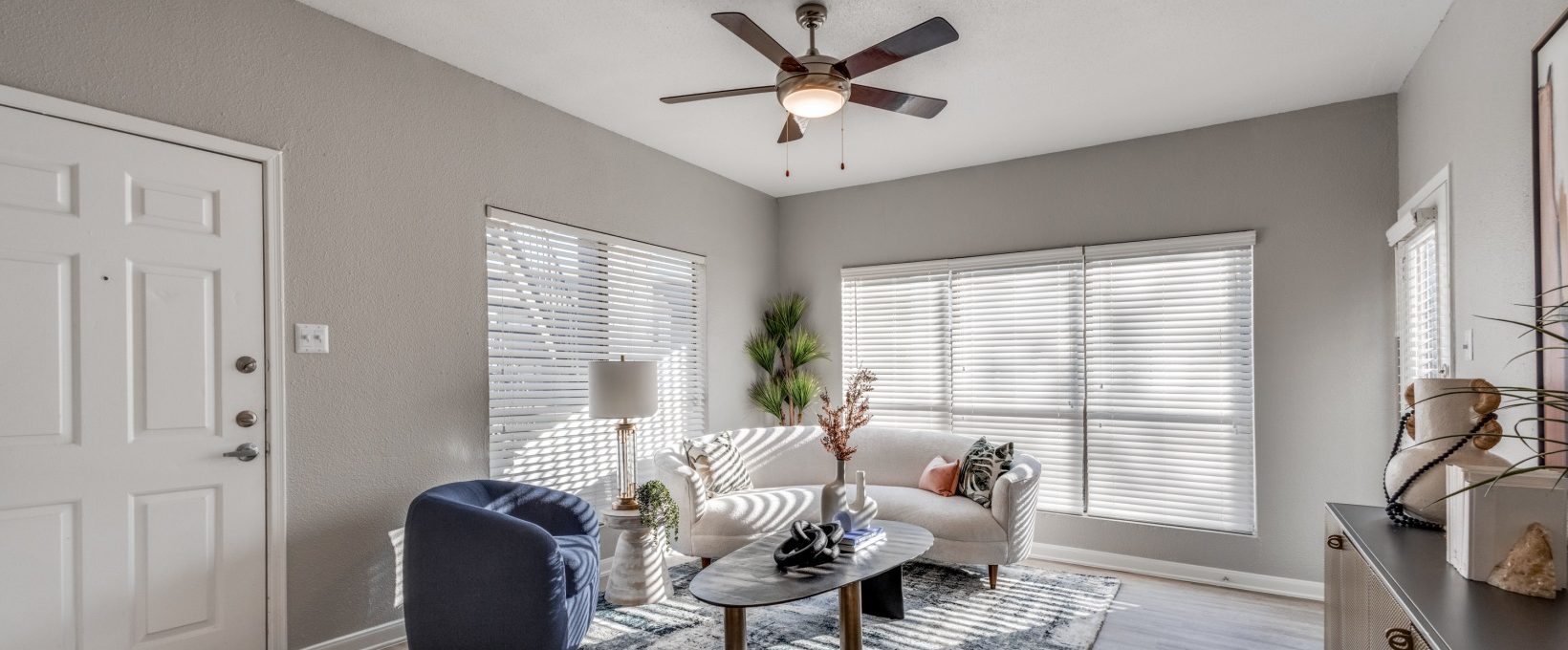 a living room with a ceiling fan and white walls at The Pearce on  Lake