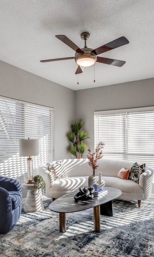 a living room with a ceiling fan and white walls at The Pearce on  Lake